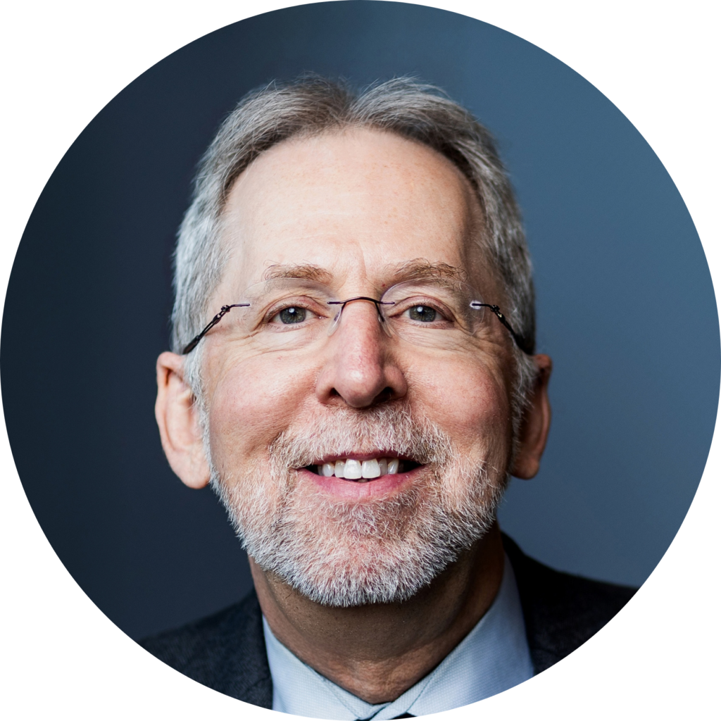 Portrait of Eric Green smiling, wearing glasses, with a grey beard and dark jacket.