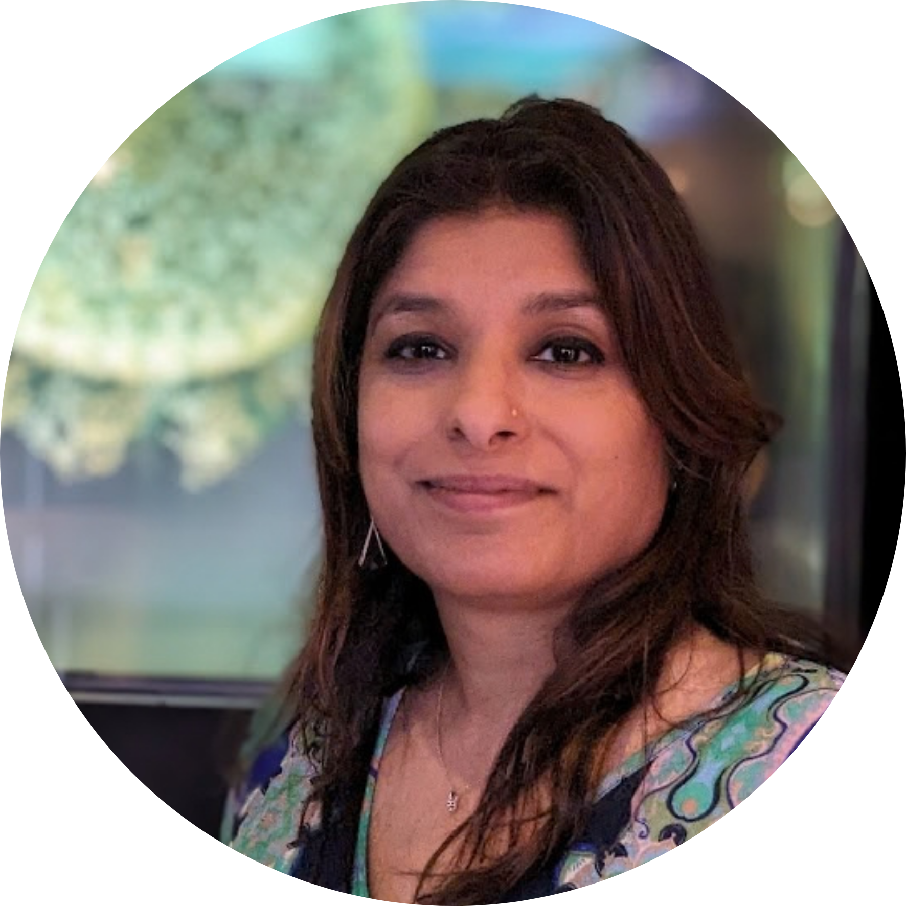 Portrait of Varsha Khodiyar with long dark hair and a patterned top.